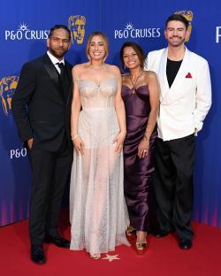 Four people posing on a red carpet at an awards ceremony.