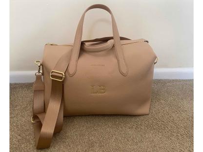 Beige Katie Loxton Milan cabin bag with gold lettering.