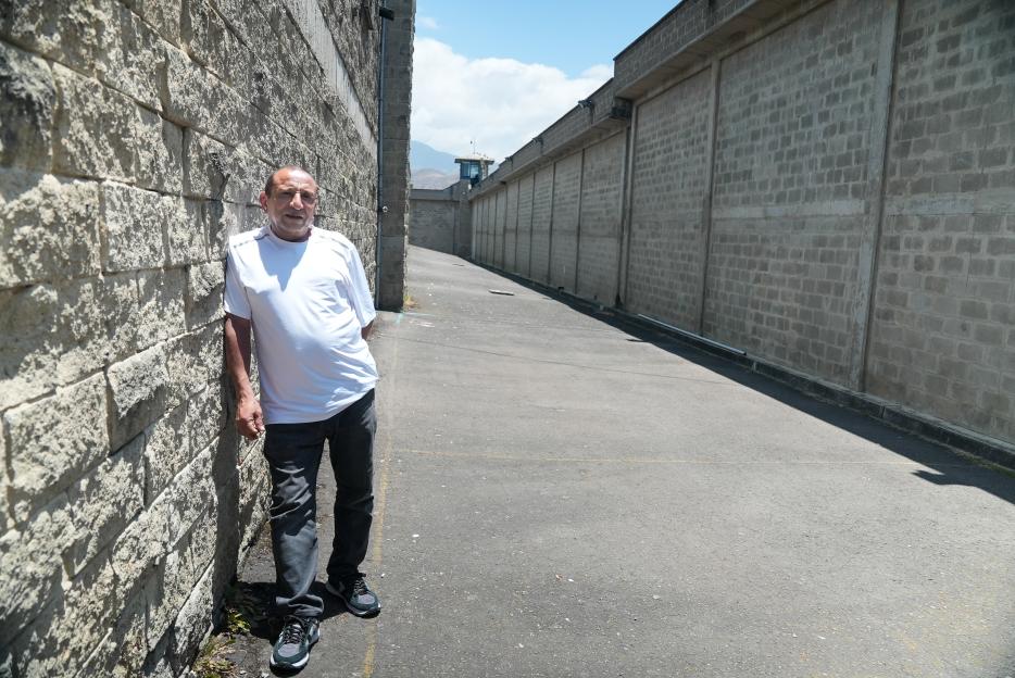 Man leaning against a prison wall.