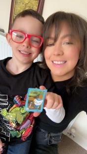 A woman and young boy holding a collectible card.
