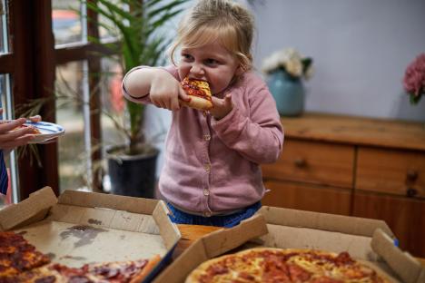 Toddler eating a slice of pepperoni pizza.