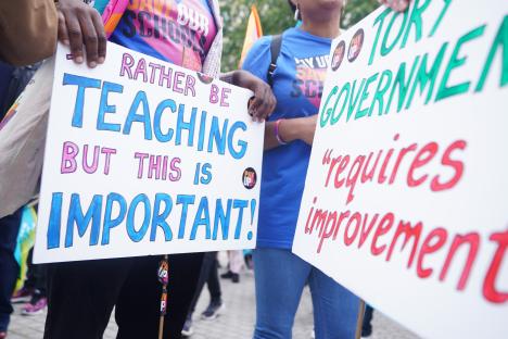 Protestors holding signs about teacher pay and the Tory government.