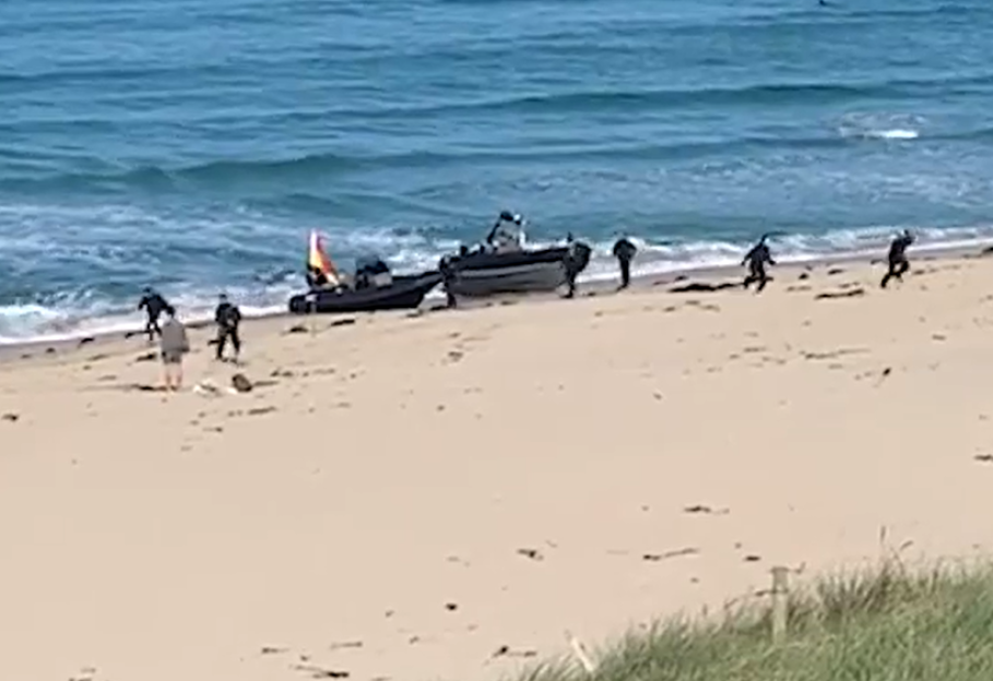 Beach with two boats and people on shore.