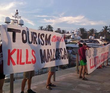 Protestors in Mallorca holding signs that say "Tourism Kills Mallorca."