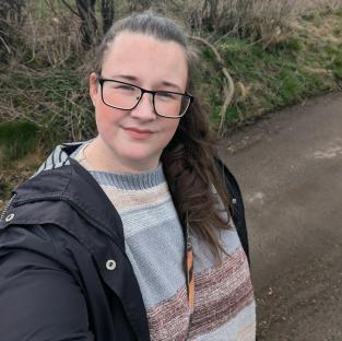 Selfie of a woman wearing glasses and a striped sweater.