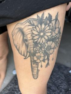 Thigh tattoo of an elephant surrounded by flowers.