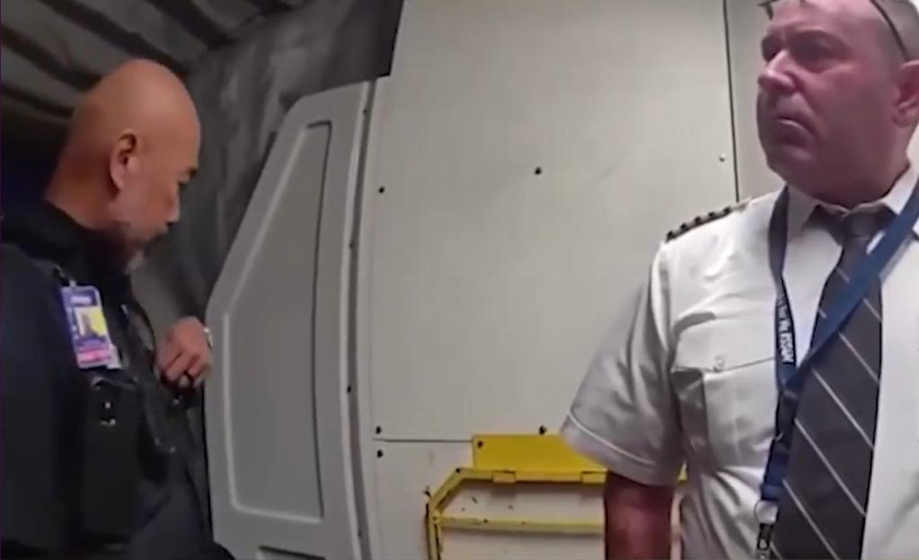 Police officer escorting a pilot from the cockpit.