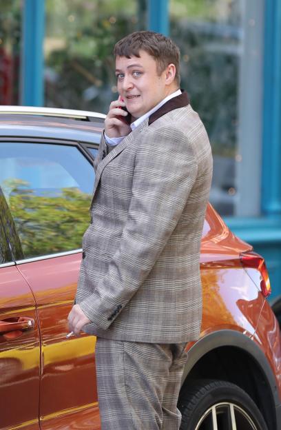Man in suit talking on cell phone outside.