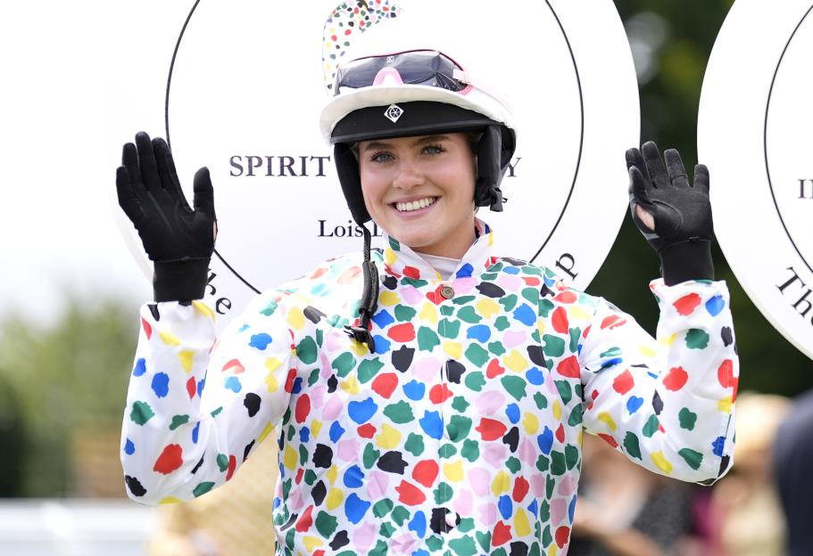 Jockey Lois Logan waving at a racecourse.