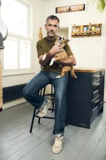 Man holding a small dog in his lap.