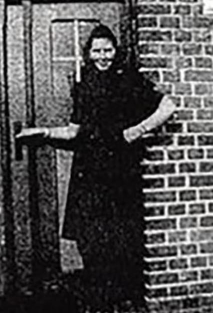Black and white photo of Irmgard Furchner, a young woman, in a long dark dress smiling.