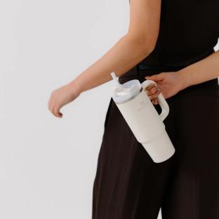 Person holding a white Stanley tumbler with a straw.