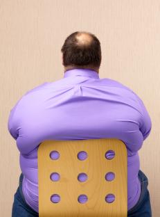 Rear view of an obese man sitting in a chair.