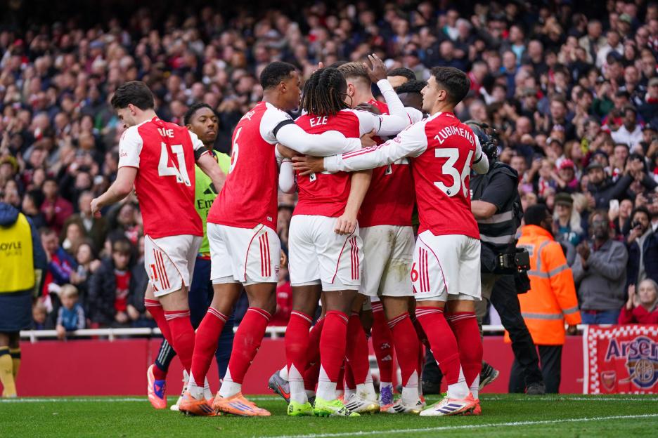 Arsenal players celebrating a goal with Bukayo Saka at Emirates Stadium.
