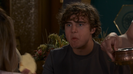 Screenshot of a young man with curly brown hair eating.