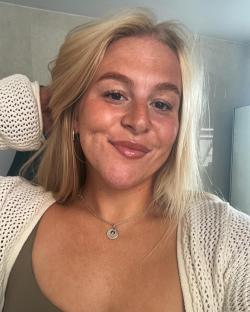 Portrait of a young woman with blonde hair wearing a cream-colored cardigan and necklace.