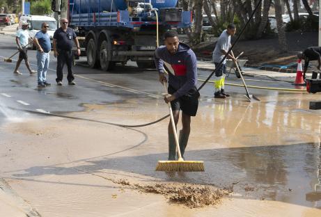 Worker clearing mud from a flooded street.