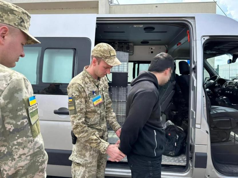 Ukrainian military police arresting a man and loading him into a van.