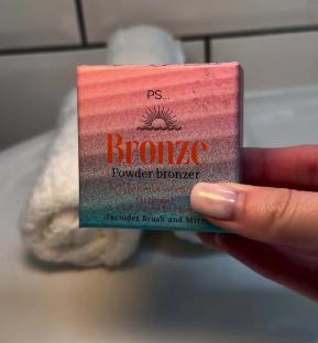 A hand holding a box of Primark's PS... Bronze powder bronzer.