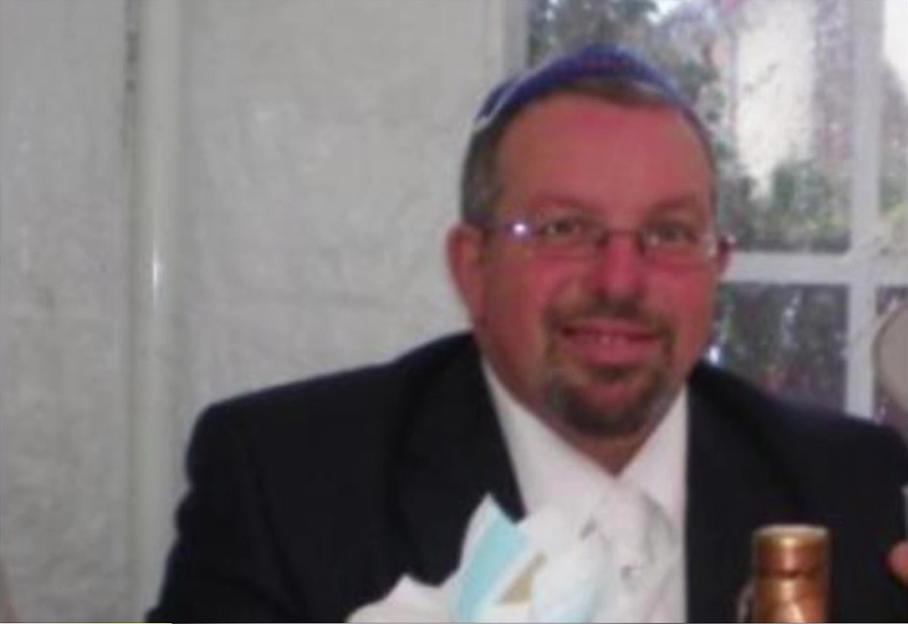 Melvin Cravitz in a headshot with a blue yarmulke and glasses.