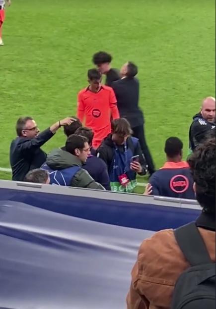 A security guard tackling a pitch invader on a soccer field, while others in the foreground watch.