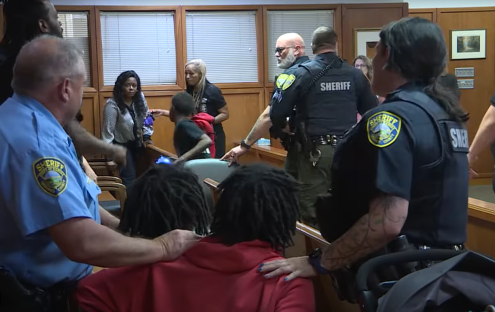 Sheriff's deputies and family members in a courtroom.