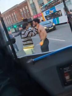 Video of a shirtless man and another man arguing in the street.