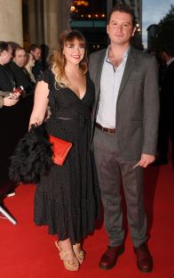 a man and a woman pose for a picture on a red carpet