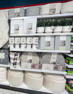 Store shelf displaying bedding, home decor, and storage ottomans.