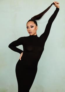 Woman in black dress holding her ponytail.