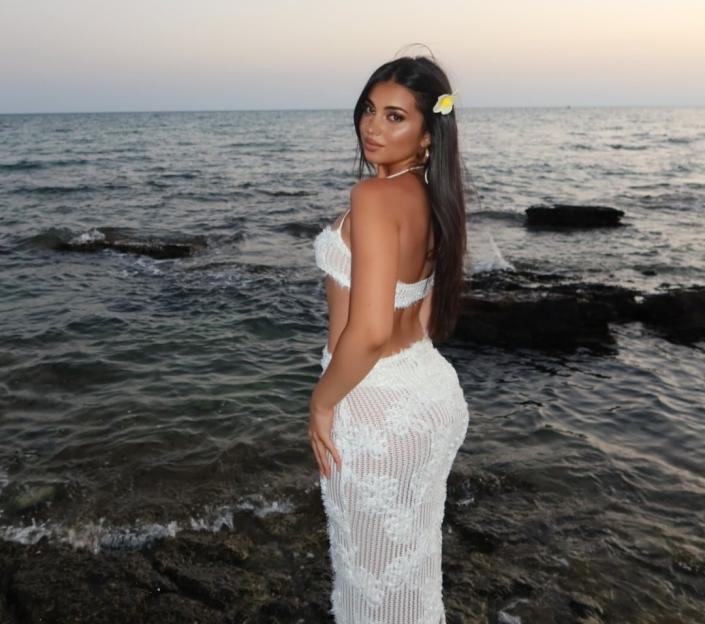 Anna Gegnoso in a white crocheted outfit by the sea.