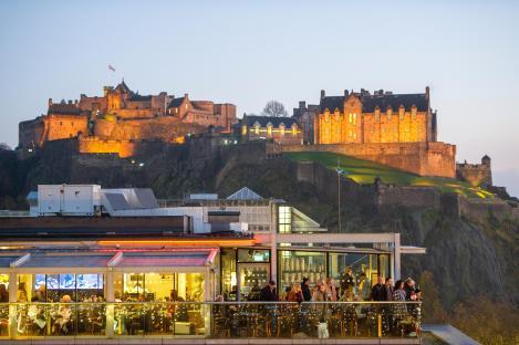 Edinburgh Castle viewed from a rooftop restaurant at dusk.