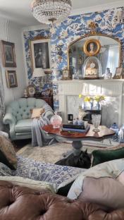 Living room with blue and white patterned wallpaper, a fireplace, and antique furniture.