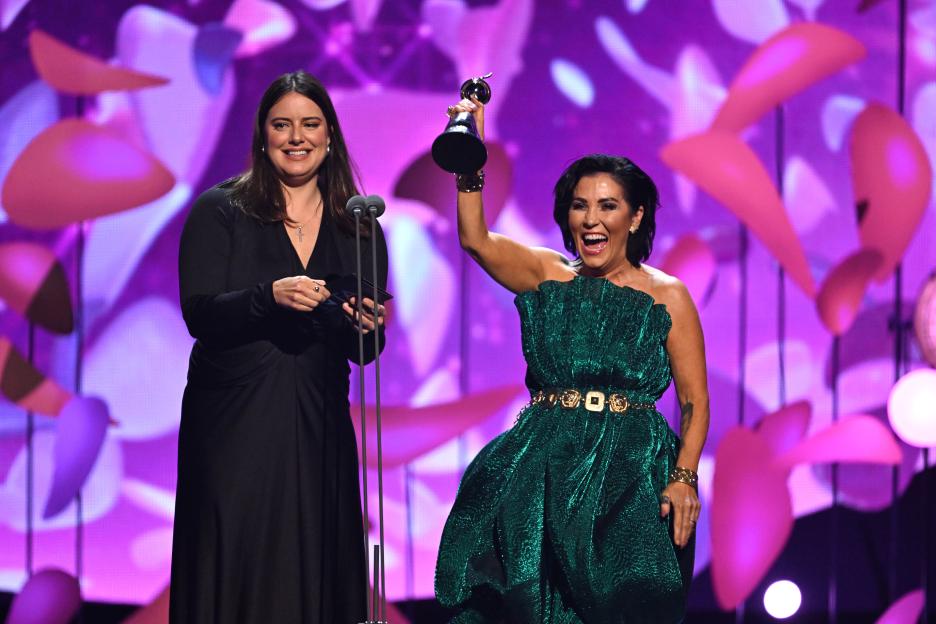 Michelle Ryan and Jessie Wallace presenting an award at an awards ceremony.