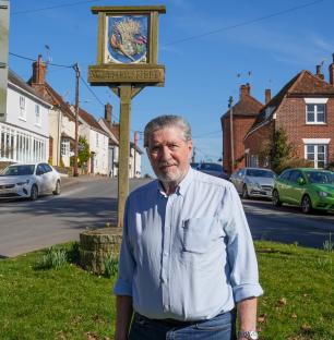 A man stands by a Wethersfield village sign.