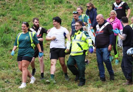 A cheese-rolling contestant being assisted by medical personnel after a race.