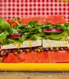 Watermelon sandwich with feta, olives, capers, cucumber, red onion, and greens.