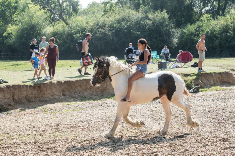 A girl riding a piebald horse in a field.