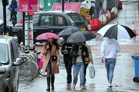 People walking in a rainy city center, using umbrellas.