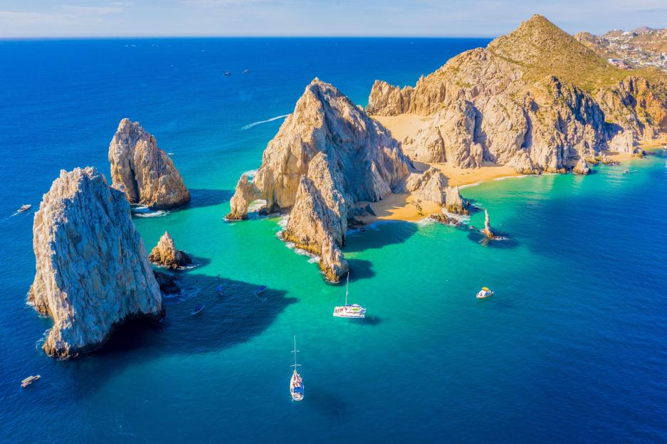 Aerial view of El Arco de Cabo San Lucas, Baja California Sur, Mexico, showing rock formations, beaches, and boats on the ocean.