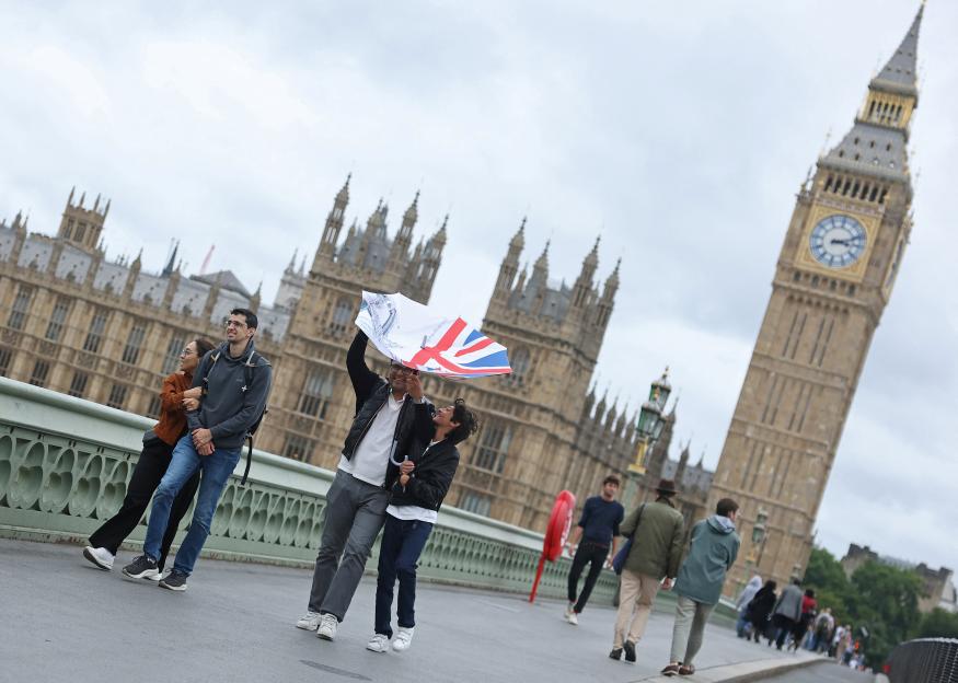 People struggle to use umbrellas in strong winds near the Houses of Parliament in London.
