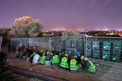 Migrant workers resting at a construction site at night.
