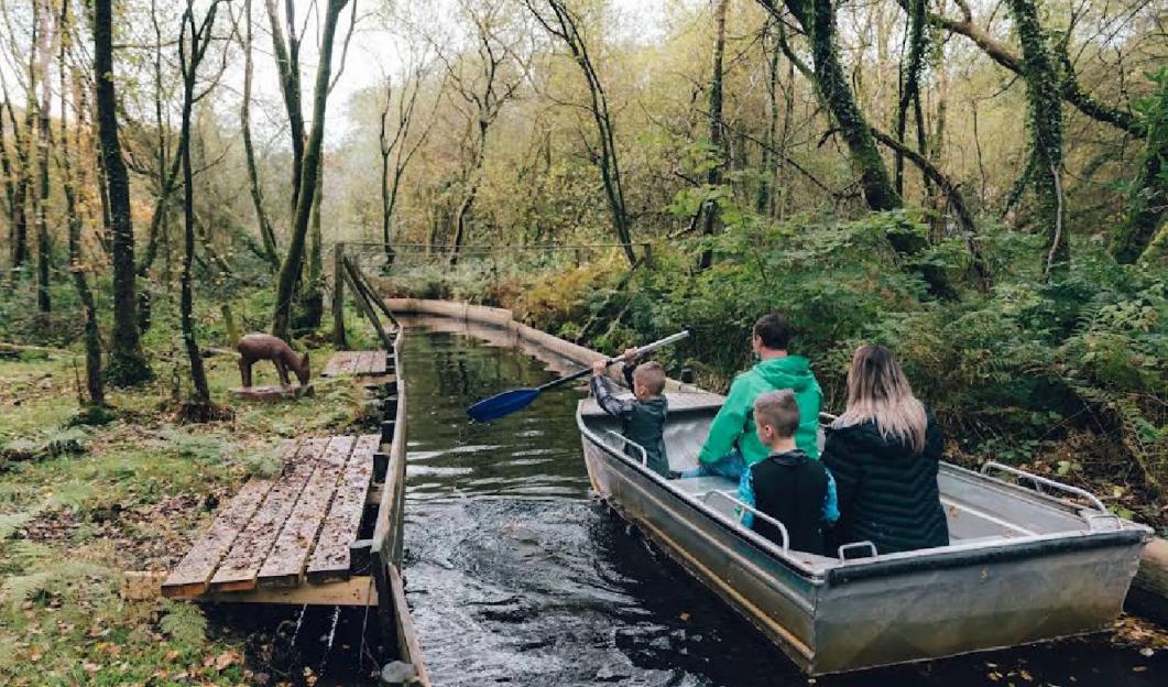 Family boating on a canal in a wooded area.