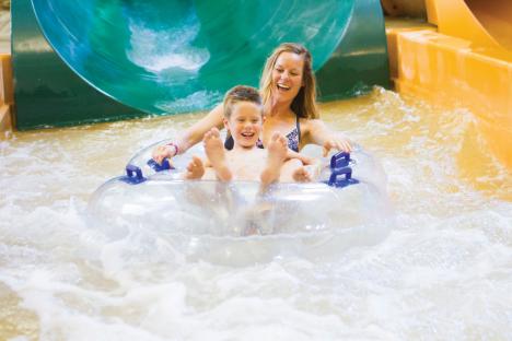 A woman and child enjoy a water park lazy river.