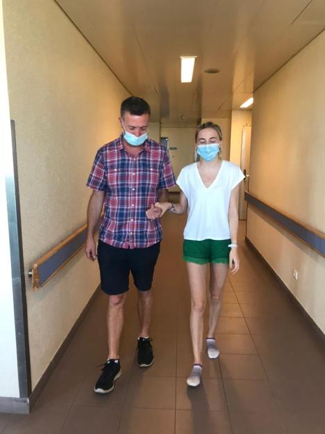 Man and woman walking down a hospital hallway, holding hands.