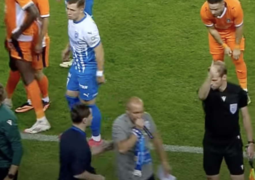 Screenshot of a soccer game referee speaking with players and coaches.