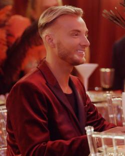 Man in a red jacket smiling at a table.