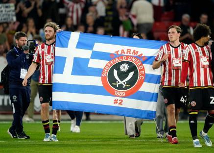 Sheffield United players holding a flag in memory of former player George Baldock.