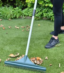 Person using a telescopic artificial grass rake.