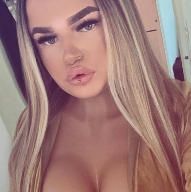 Portrait of a woman with long blonde hair and lip piercings.